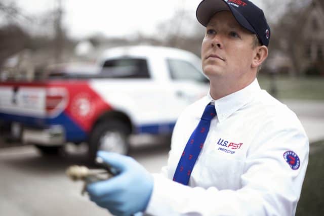 A U.S. Pest Protection technician spraying for mosquitoes and ticks.