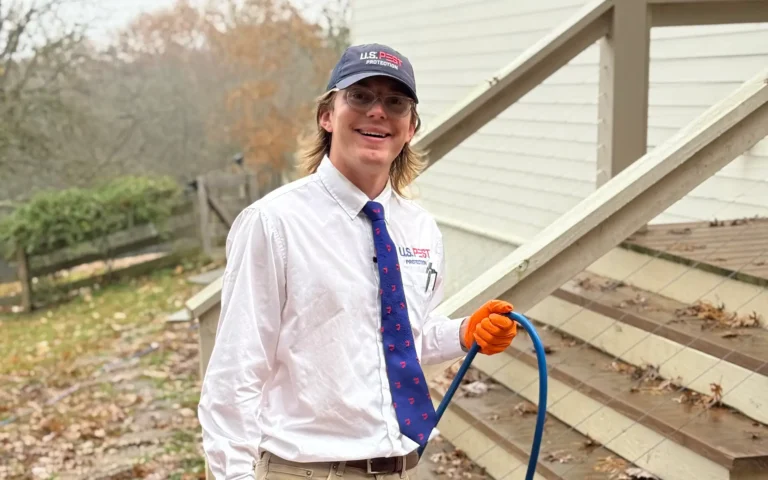 U.S. Pest technician in professional attire standing outside a customer’s home.