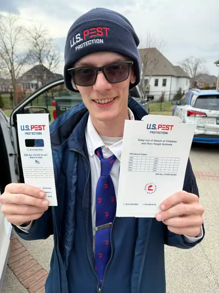 U.S. Pest technician applying preventative pest treatment around a home exterior