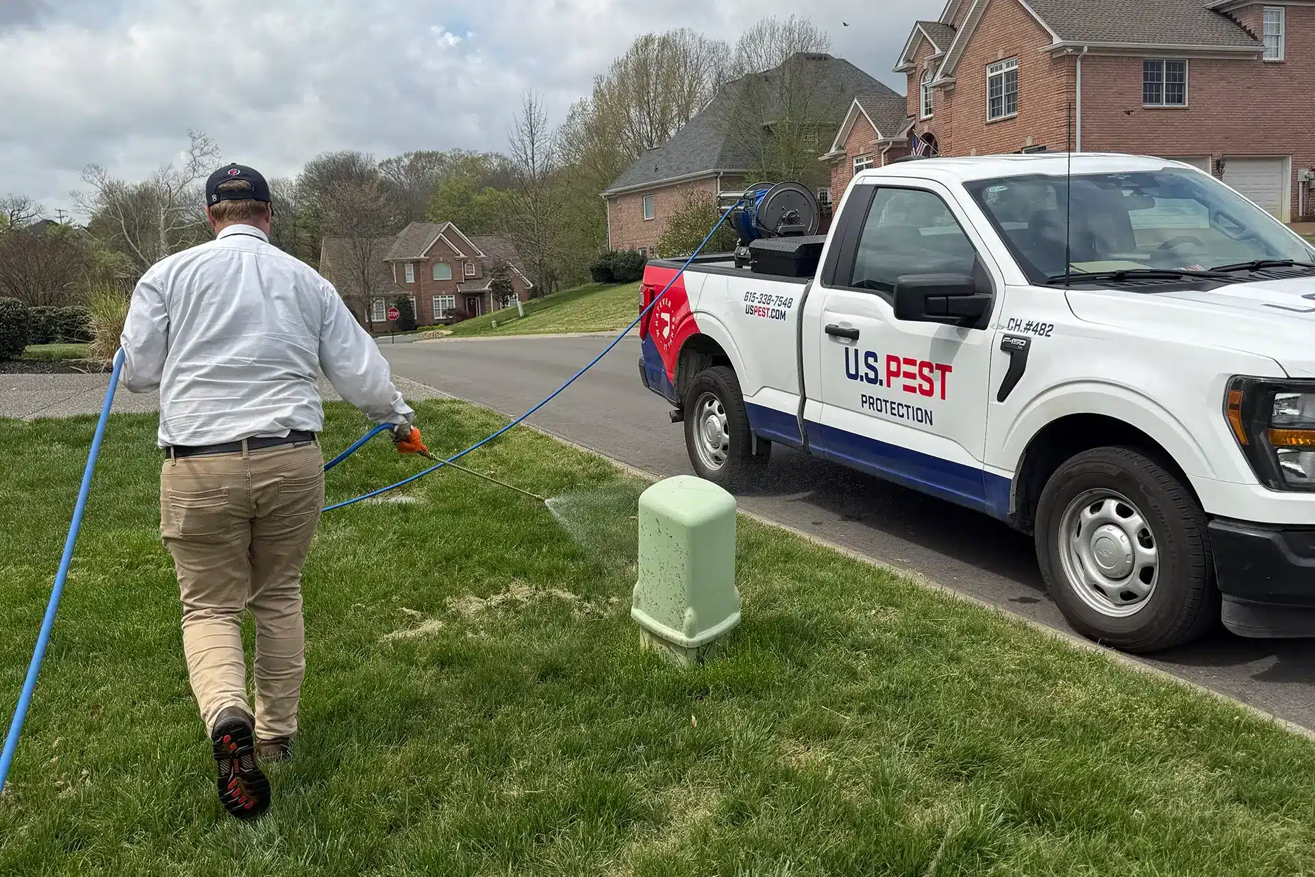 U.S. Pest Protection technician applying a mosquito barrier treatment to a yard.