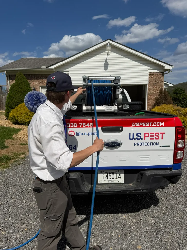 U.S. Pest technician performing a spring perimeter treatment around a home