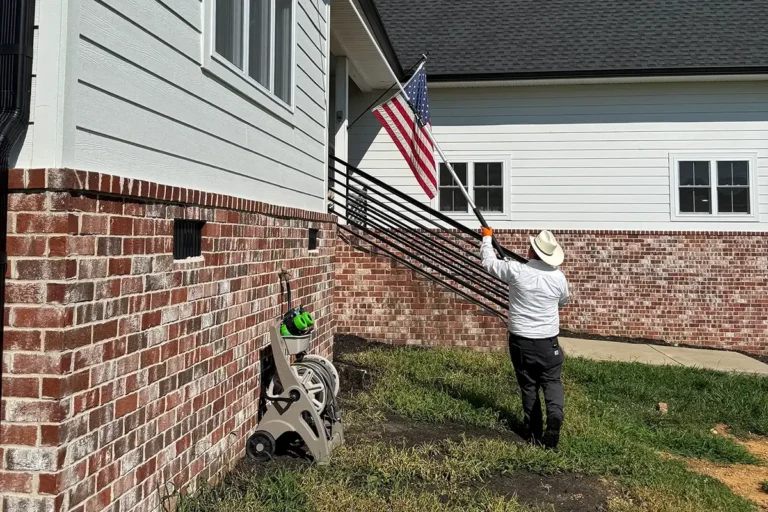 U.S. Pest Protection technician performing a late-summer perimeter inspection at a residential home