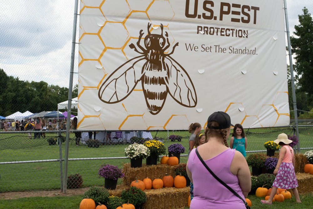 Families at the Tennessee Honey Festival in front of a U.S. Pest Protection bee banner